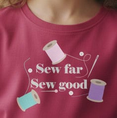 Person wearing a T-shirt with the phrase Sew far sew good and illustrated spools of thread across the chest.