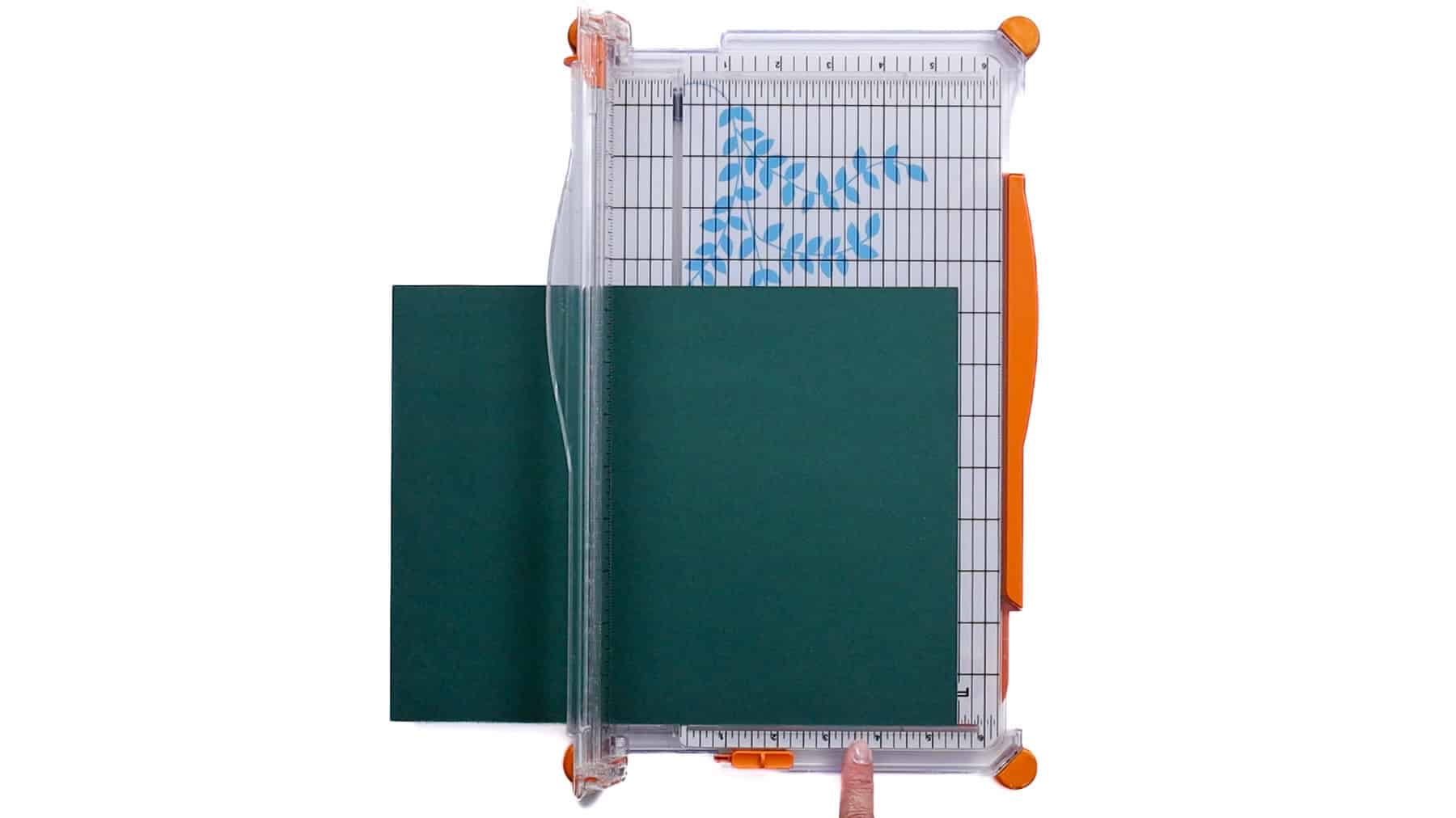 Paper aligned on a paper cutter with grid lines and a sliding blade, ready to trim a straight edge