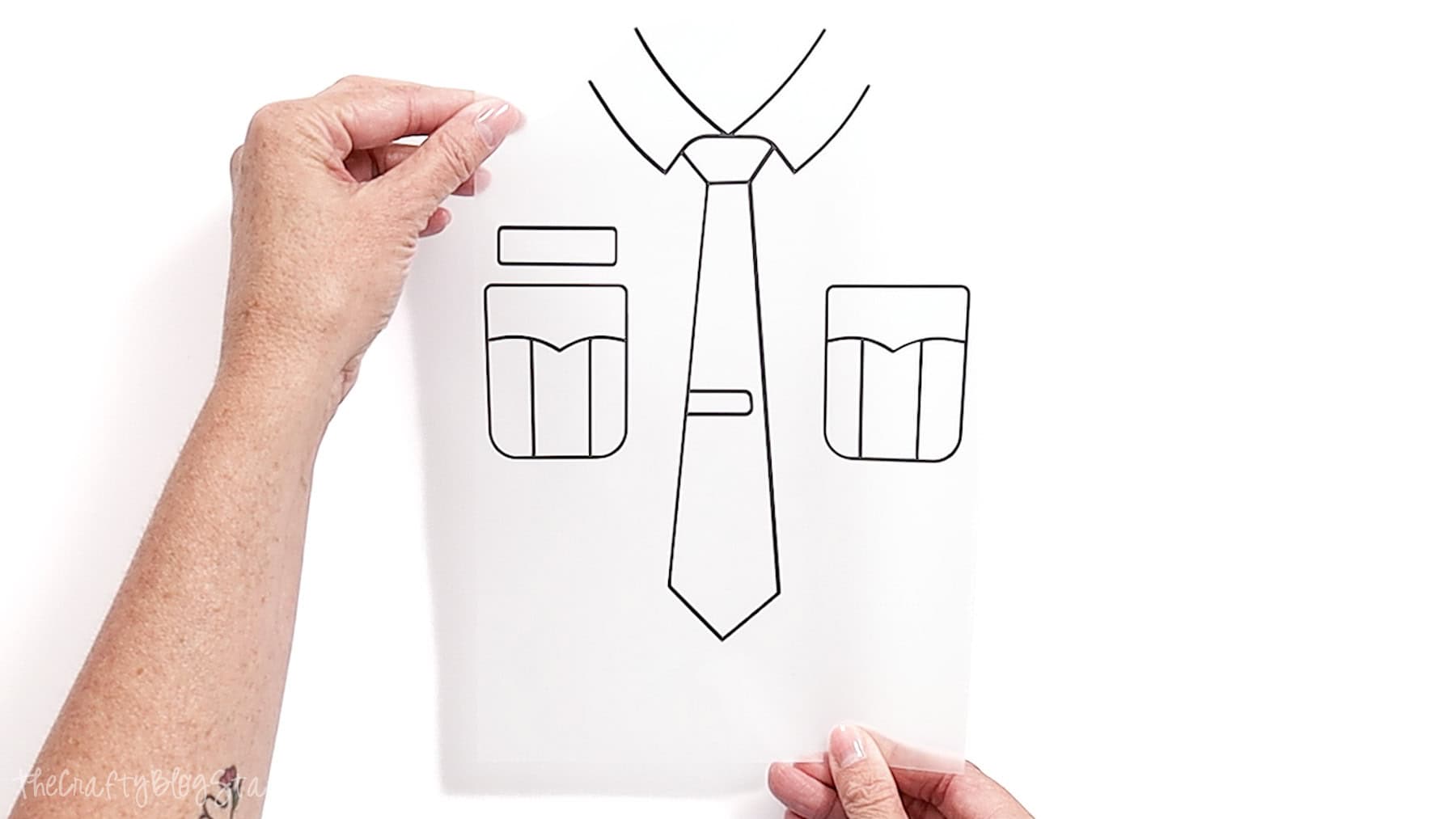 Hands holding clear transfer sheet with weeded police uniform vinyl design, showing tie, pockets, and collar ready for heat transfer