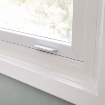 Close-up of a white painted window trim and sill above a light green wall, showing clean molding details and a freshly finished surface.