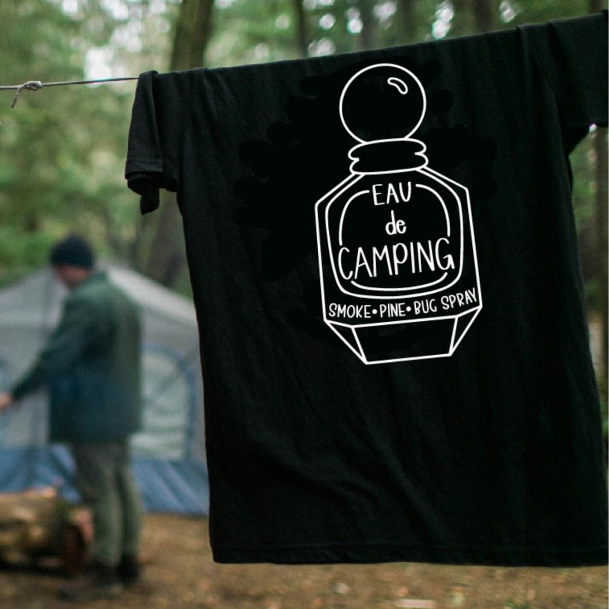 Black camping-themed T-shirt hanging on a clothesline with a humorous