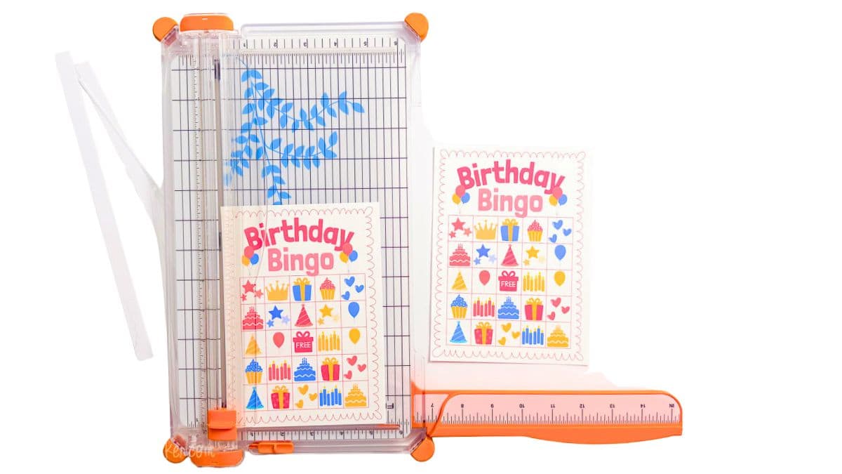 Paper trimmer cutting printed Birthday Bingo cards into individual game cards after printing two cards per page.