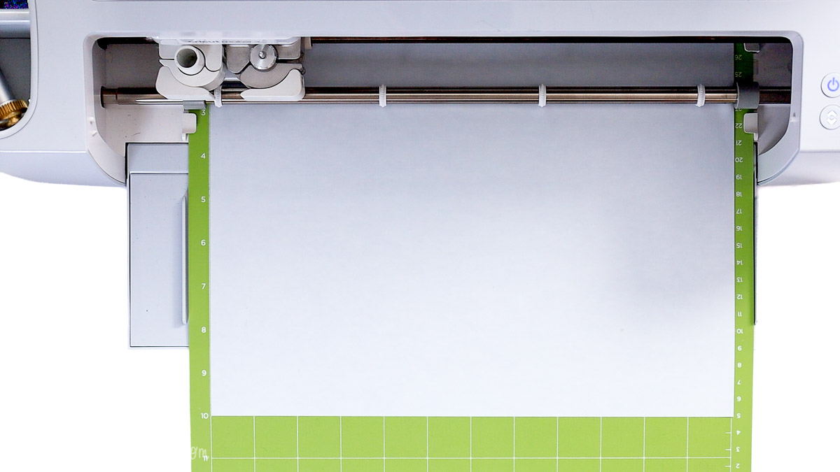 Cricut cutting machine with a green cutting mat loaded and ready to cut heat transfer vinyl for a DIY wood sign project.