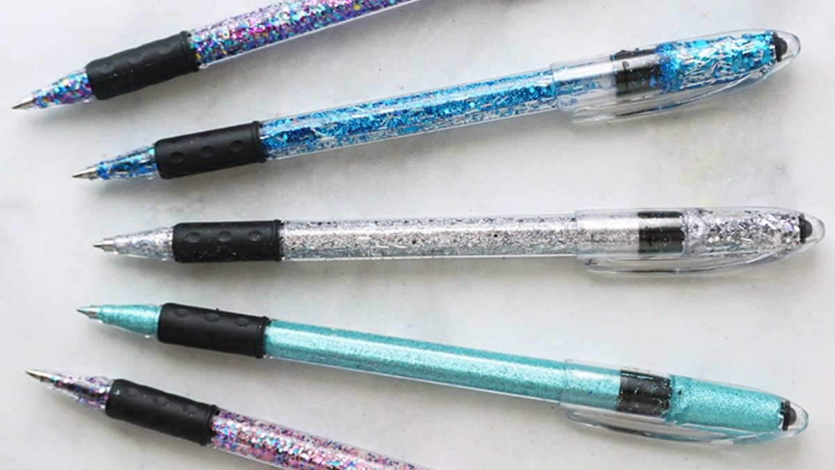 Five DIY glitter pens with clear barrels filled with blue, silver, turquoise, and multicolor glitter displayed on a white background.