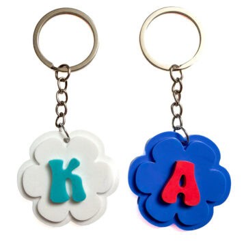 Two finished flower-shaped resin letter keychains with silver key rings, featuring a white K design and a blue A design on a white background.