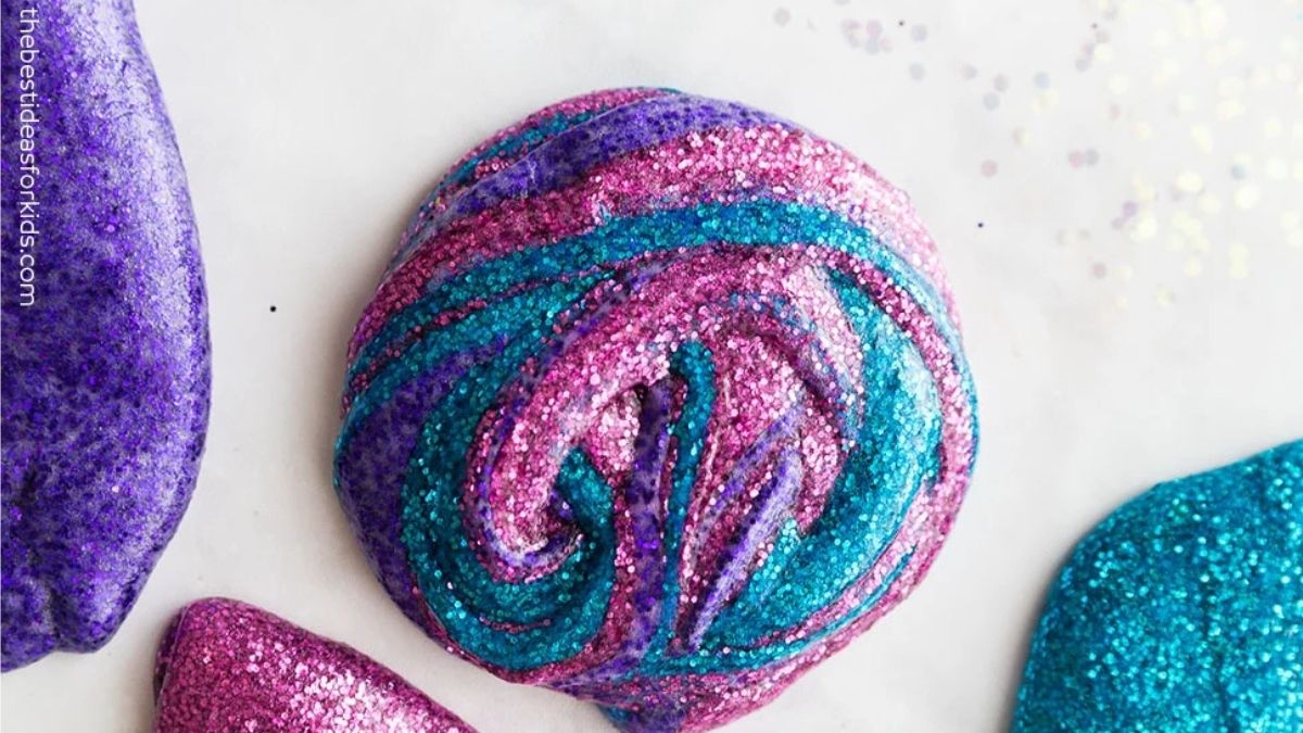 Close-up of homemade glitter slime swirled with pink, purple, and teal glitter, creating a colorful marbled pattern with a sparkly finish.