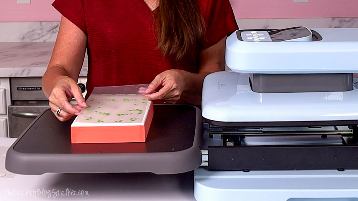 Applying the green heat transfer vinyl layer to a whitewashed wood sign using an HTVRont Auto Heat Press 2.