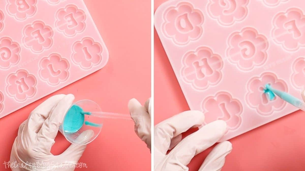 Gloved hands pour turquoise-tinted resin into a flower-shaped silicone mold using a pipette to create personalized resin keychains.