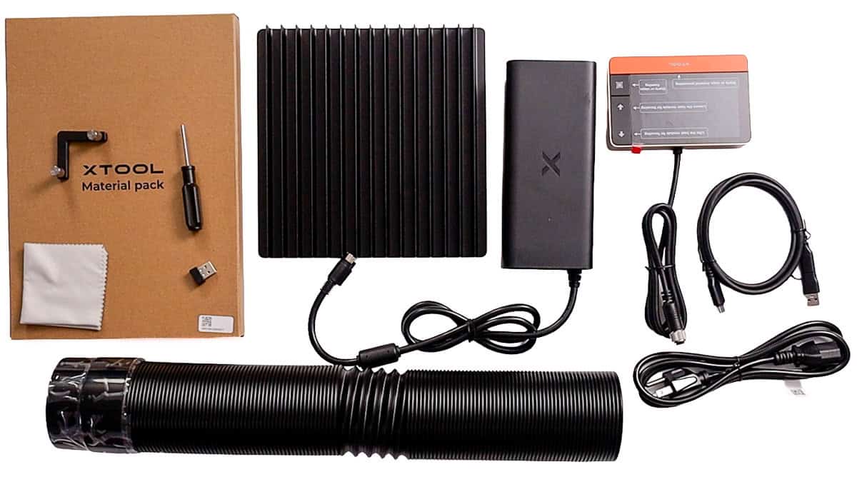 xTool F2 Ultra accessories and setup kit, including material pack, exhaust hose, power adapter, touchscreen controller, cables, screwdriver, and cleaning cloth.