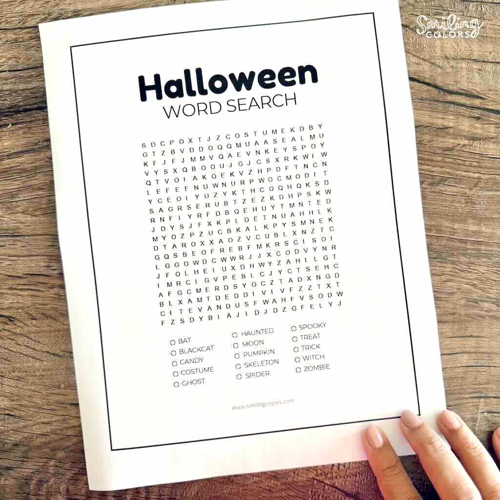 Printable Halloween word search puzzle with a letter grid and a list of spooky words, displayed on a rustic wooden table.