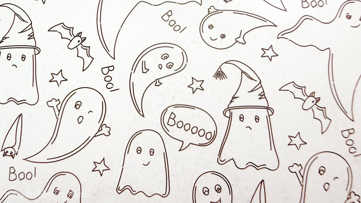 Close-up of a laser-engraved Halloween pattern featuring playful ghosts, bats, stars, witch hats, and Boo lettering on wood.