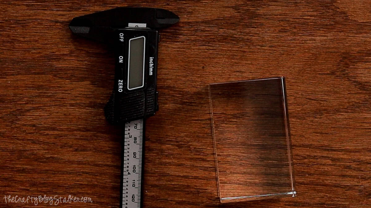 Digital calipers and a clear rectangular crystal blank on a wooden surface, ready for measuring before a 3D inner laser engraving project.