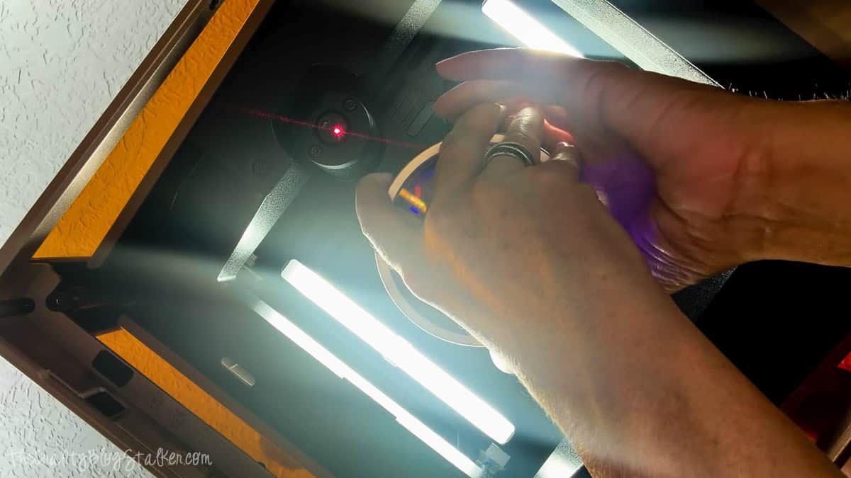 Hands installing the rotating lens inside an xTool F2 Ultra laser while aligning the red positioning laser for inner engraving.