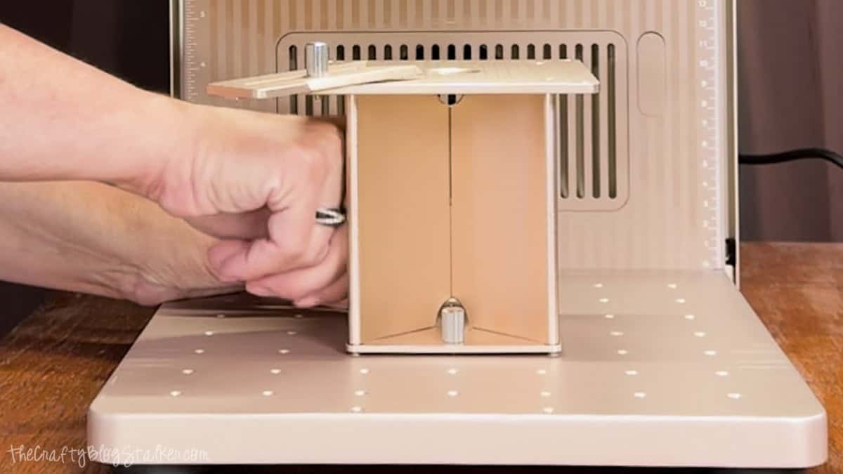 Hands adjusting the crystal engraving jig inside an xTool F2 Ultra laser before starting a 3D inner engraving project.