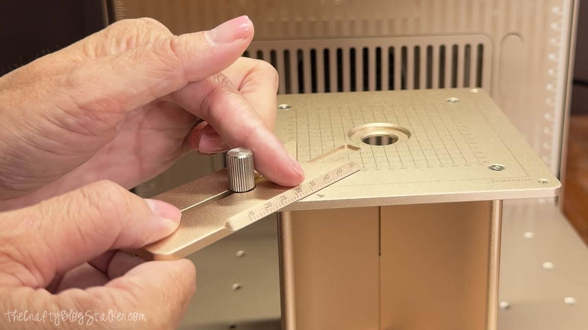 Hands adjusting the alignment guide on the xTool F2 Ultra crystal jig to position a crystal block for accurate 3D inner engraving.