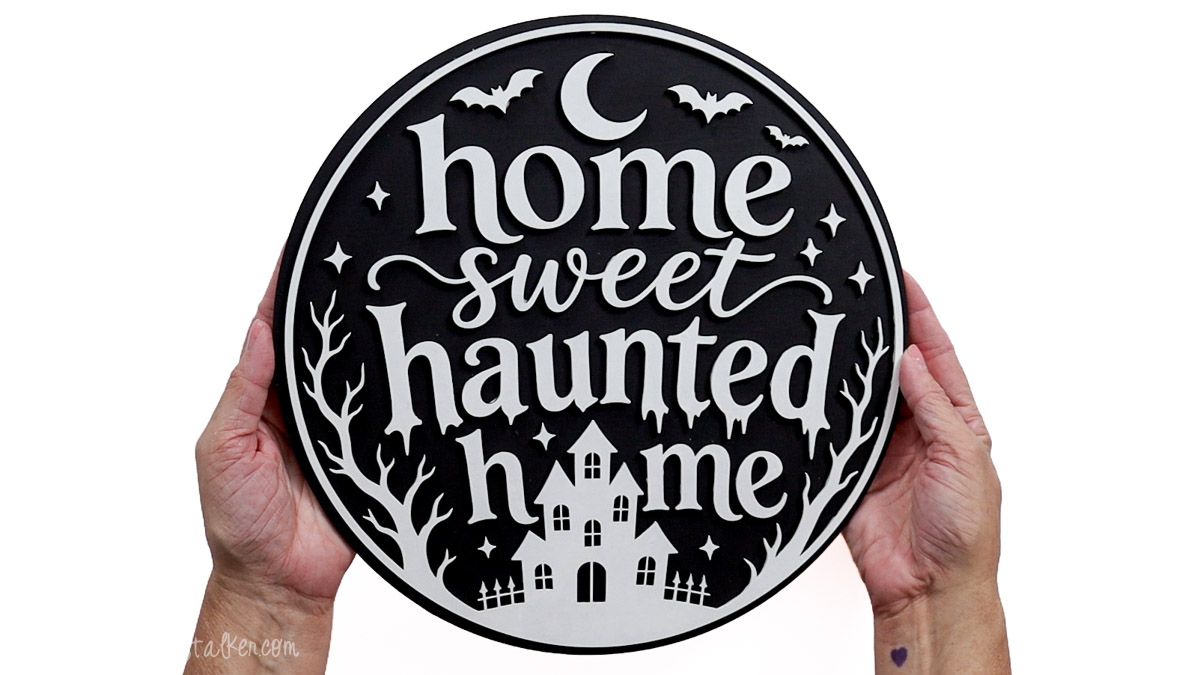 Finished black and white Home Sweet Haunted Home sign with a haunted house, bare trees, bats, crescent moon, and stars.