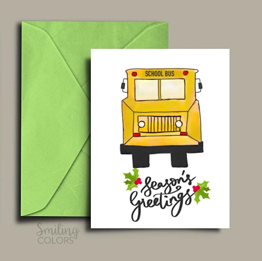 Printable bus driver Christmas card with a yellow school bus, Season's Greetings lettering, holly accents, and a green envelope.