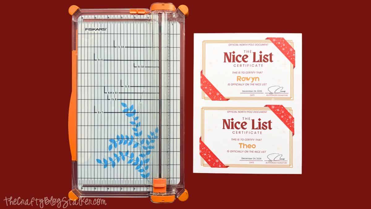 Fiskars paper trimmer beside two personalized printable Nice List certificates for Rowyn and Theo on a dark red background.