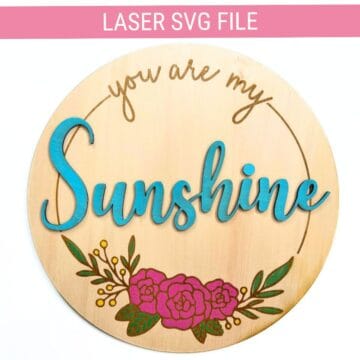 Round wooden sign with layered blue “Sunshine” text, engraved “you are my” above, pink flowers at the bottom, and a “Laser SVG File” banner at the top