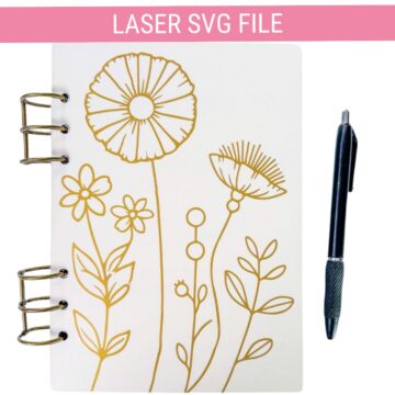 Laser SVG file featuring a floral line art design engraved on a white ring-bound notebook, shown beside a black pen.