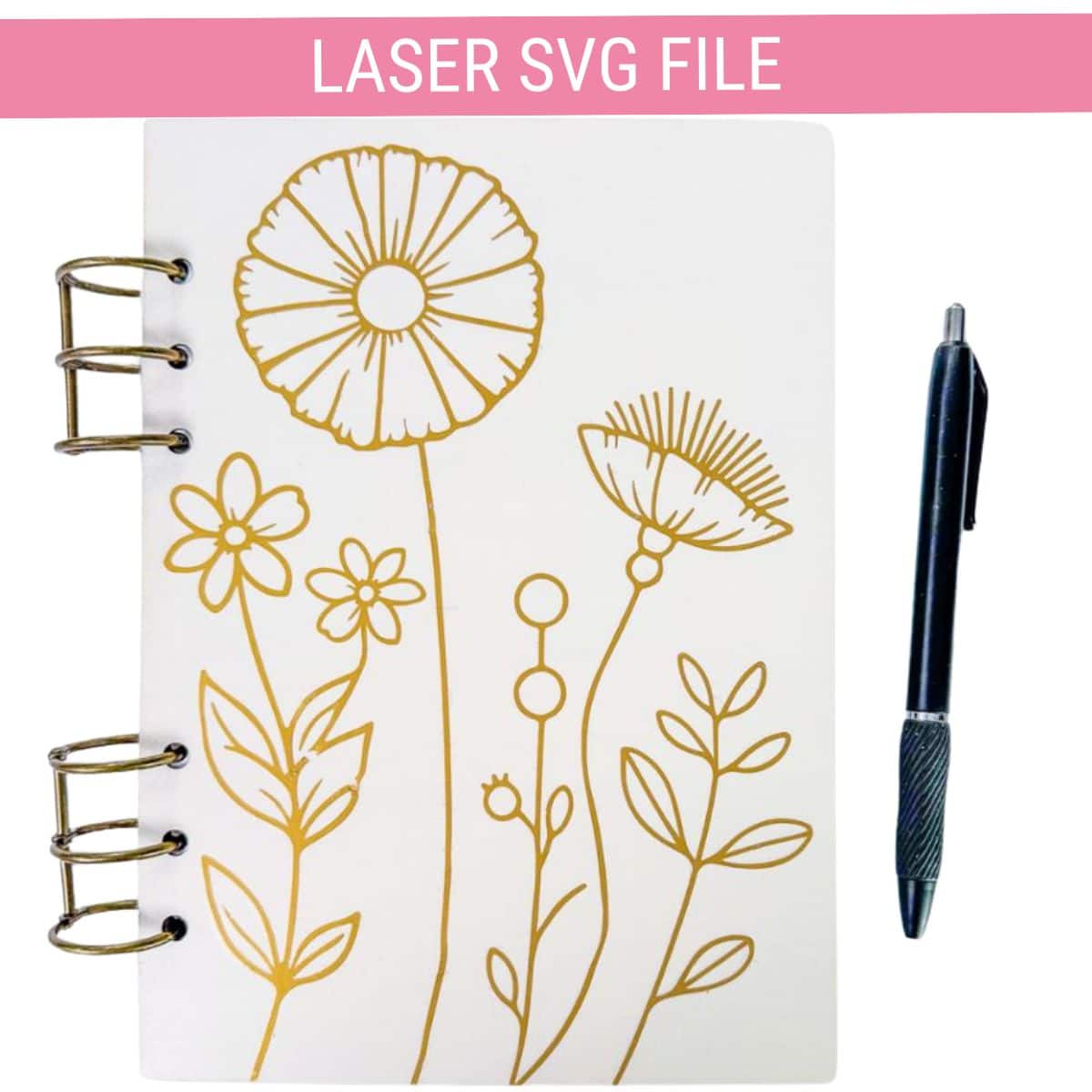 Laser SVG file featuring a floral line art design engraved on a white ring-bound notebook, shown beside a black pen.