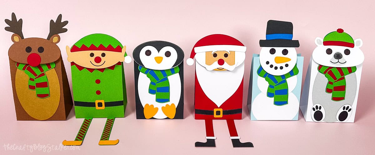 Three festive Christmas gift bags decorated as a reindeer, elf, and snowman, made from colorful paper with fun holiday details.