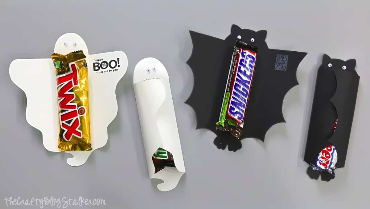DIY Halloween candy bar covers shaped like ghosts and bats, each holding wrapped chocolate bars like Twix, Snickers, and Milky Way with googly eyes attached.