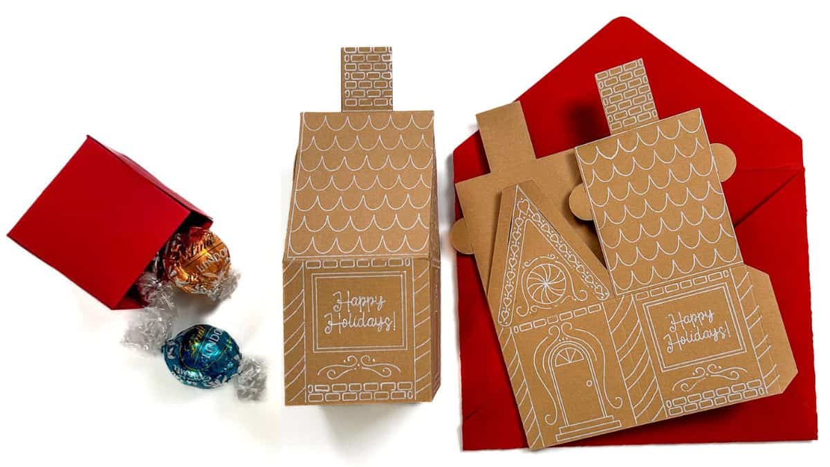 DIY gingerbread house Christmas cards with red envelopes and a small red treat box filled with chocolate truffles.
