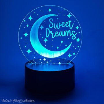 Round acrylic night light engraved with a crescent moon, stars, and the words “Sweet Dreams,” displayed on a small base.