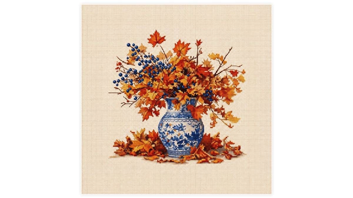 Preview of a printable cross stitch featuring a blue and white vase filled with autumn leaves and blue berries on cream Aida cloth.