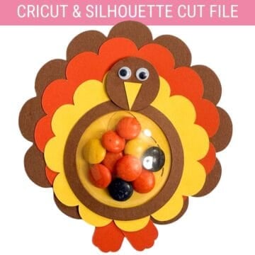 Paper turkey candy holder made with a Cricut cut file, featuring layered feathers, googly eyes, and a clear dome filled with colorful candy.
